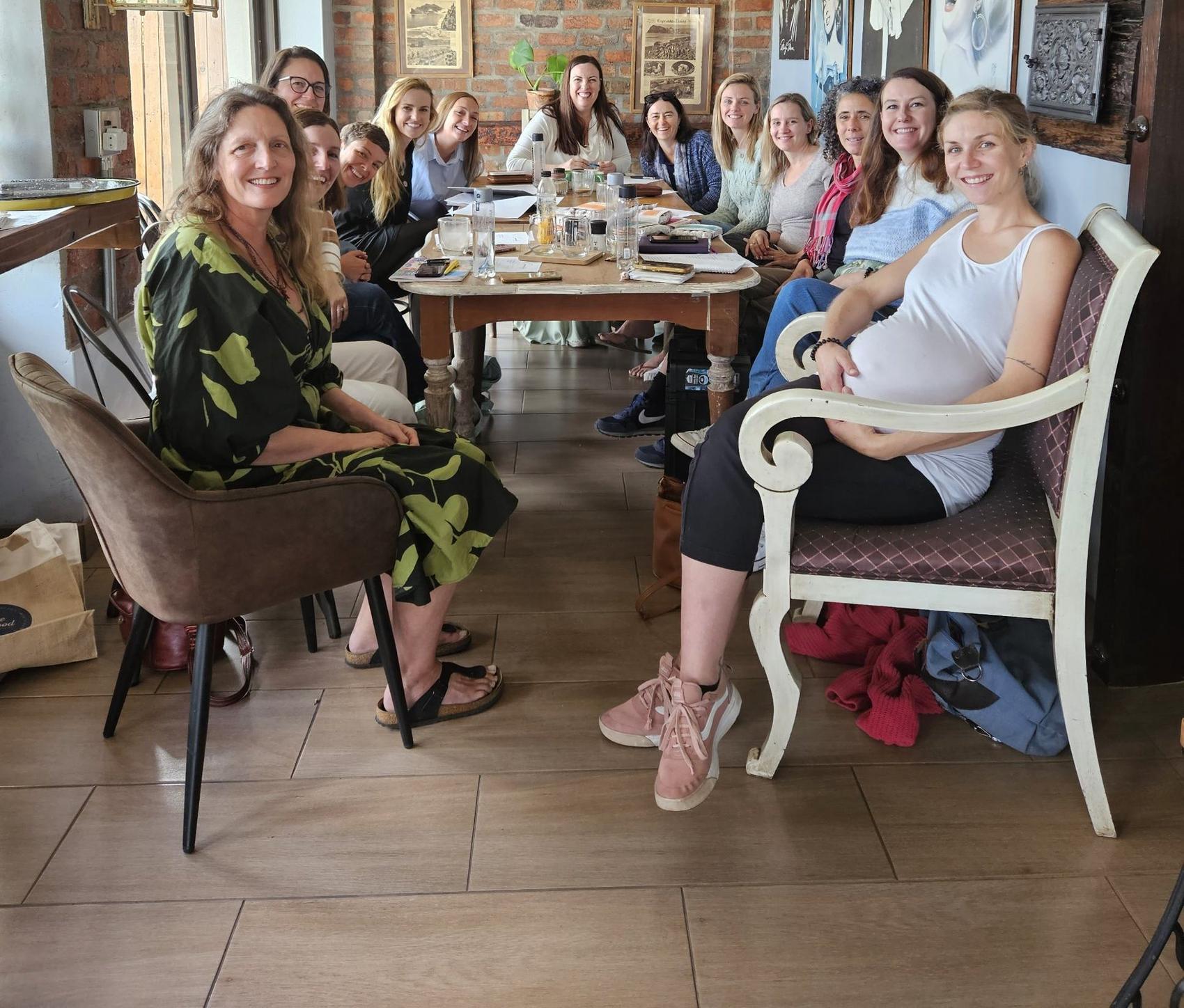 A Boss Moms pod meetup: members smiling around a long table