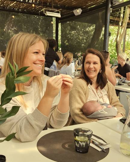 Two members laughing together, one holding her baby